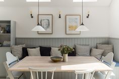 a kitchen table with four chairs and a bench in front of it, next to two pictures on the wall