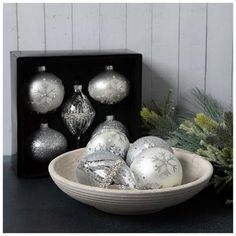 a bowl filled with silver and white ornaments