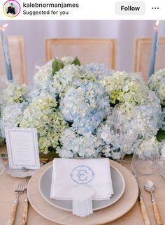 the table is set with blue and white hydrangeas, napkins, and silverware