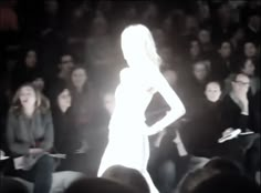 a woman is walking down the runway at a fashion show