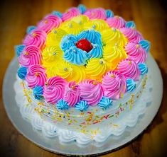 a colorful cake with icing and sprinkles on a wooden table top