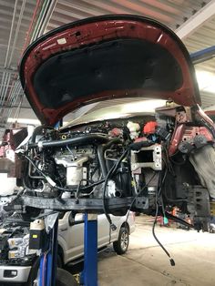 a car is being worked on in a garage with its hood up and the engine exposed