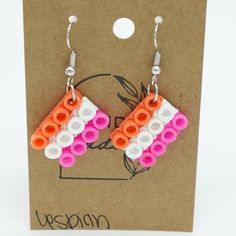 the earrings are made out of legos and have white, orange, and pink beads