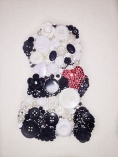 a white and black dress made out of buttons on a tablecloth with a red heart in the center