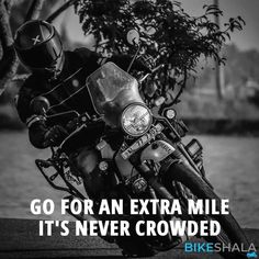 a motorcycle parked next to a tree with the words go for an extra mile it's never crowded