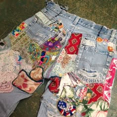 several pairs of jean shorts are laying on the floor next to each other, all with different designs and colors