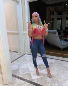 a woman with pink and green hair standing in front of a doorway holding two fingers up