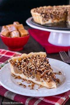 a slice of pecan pie on a plate with a fork and bowl in the background