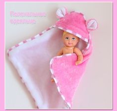 a small doll is wrapped in a pink towel