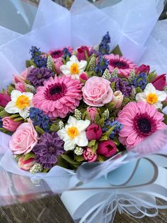 a bouquet of pink and purple flowers sitting on top of a wooden table