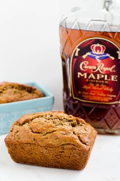 two muffins sitting next to a bottle of maple syrup on a white surface