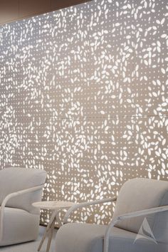 two white chairs sitting next to each other in front of a wall