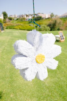 a white flower hanging from a string in the grass