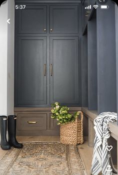 an entryway with gray cabinets and a rug on the floor, black boots in front of it