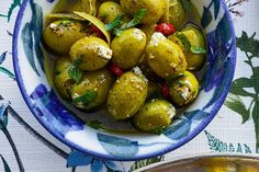 a blue and white bowl filled with pickles on top of a floral table cloth