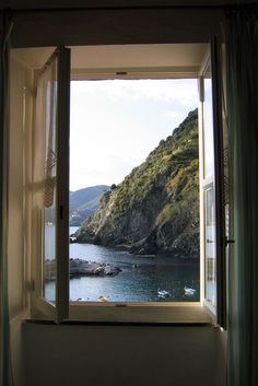 an open window looking out at the ocean and mountains in the distance with boats on the water