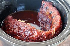 two pieces of meat in a slow cooker with bbq sauce on the side