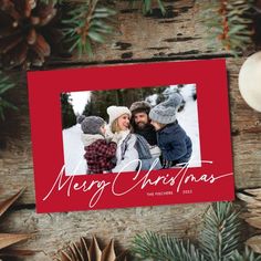 a christmas card with the words merry christmas on it and two children in front of pine cones