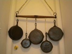 five pans hanging from a chain on the wall