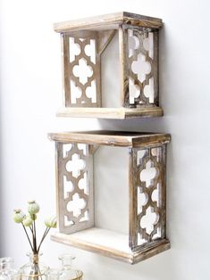 two wooden shelves on the wall with flowers in vases