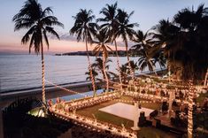 an aerial view of a wedding venue on the beach at dusk with palm trees in the foreground