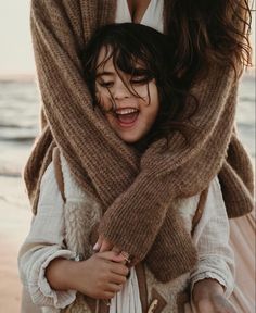 a woman is hugging a child on the beach