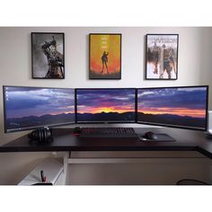 three computer monitors sitting on top of a desk