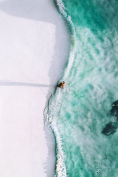 an aerial view of the ocean and beach with people swimming in it, from above