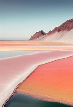 the water is pink and green in this desert landscape, with mountains in the background