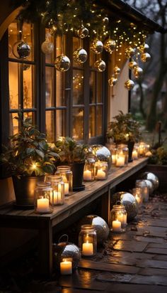 many lit candles are lined up on the side of a building with potted plants