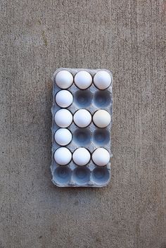 an egg carton filled with white eggs on top of a gray carpeted floor