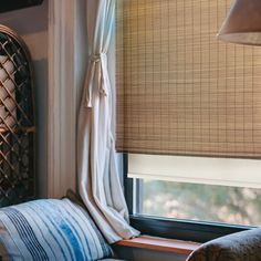 a window seat in front of a window with bamboo blinds