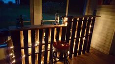 a balcony with lights on the railing, and a bar stool in front of it