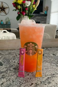 two drinks sitting on top of a counter next to some candy bar wrappers and flowers