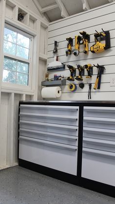 a garage with tools on the wall and two large drawers in front of it,