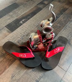 a pair of flip flops sitting on top of a wooden floor next to an elephant statue