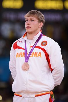 a man standing on top of a basketball court with a medal around his neck and hands behind his back