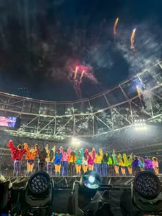 fireworks are lit up in the stadium as people stand on stage with their hands raised