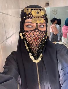 a woman wearing a black veil and headpiece with gold coins on it's face