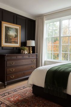 a bedroom with a bed, dresser and large window