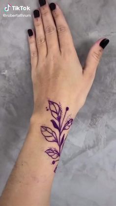 a woman's hand with a purple flower tattoo on it