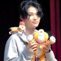 a young man holding two stuffed animals in his hands and looking at the camera with an angry expression on his face