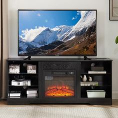 a flat screen tv sitting on top of a black entertainment center next to a fire place