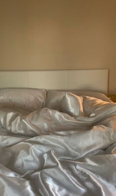 an unmade bed with white sheets and pillows