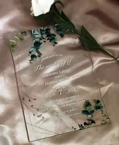 a glass award sitting on top of a bed next to a white rose and green leaves