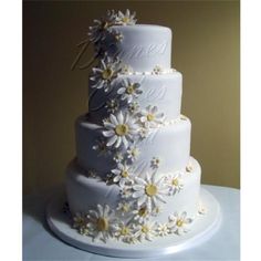 a white wedding cake with daisies on it