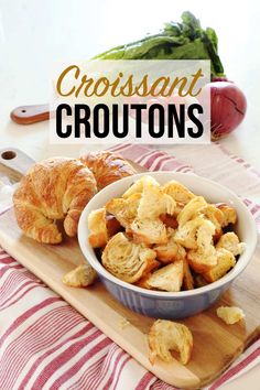 croissant croutons in a bowl on a cutting board with bread and vegetables