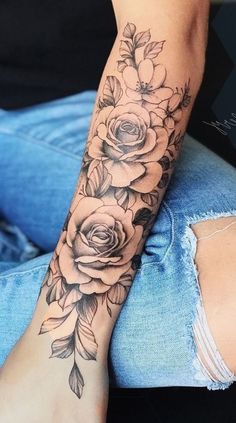 a woman's arm with flowers and leaves tattooed on the side of her leg