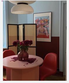 a vase with flowers sitting on top of a table in front of two red chairs