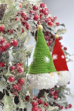 two knitted christmas hats hanging from a tree